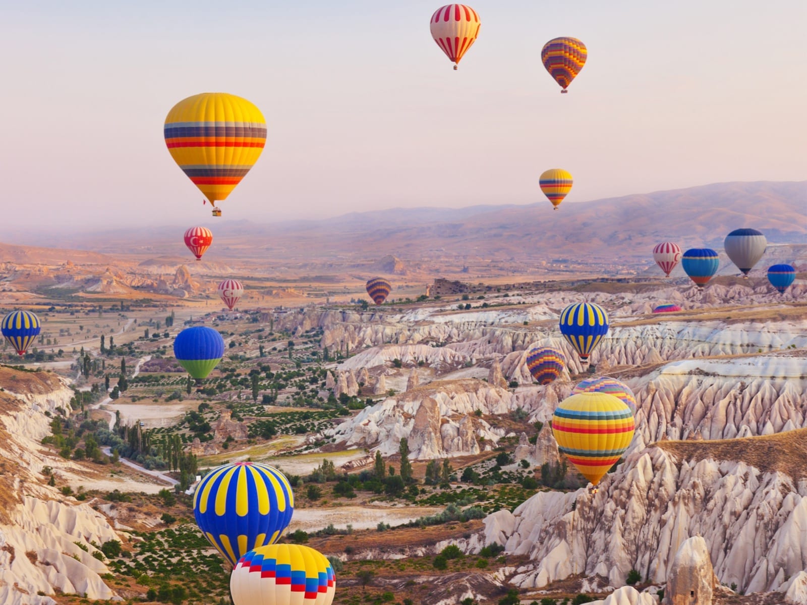 Dozens of hot air balloons over Cappadocia's fairy chimney valleys at sunrise